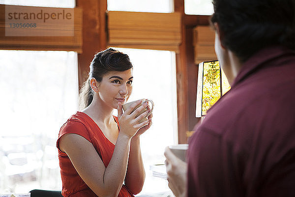 Frau trinkt Kaffee und sieht Mann im Café an
