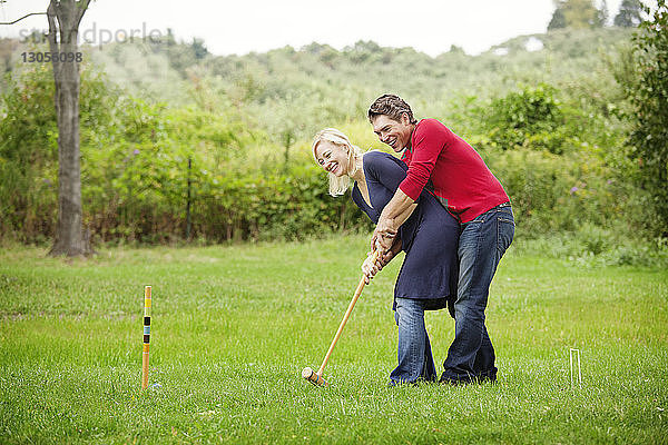 Krocketspiel eines Paares auf Grasfeld