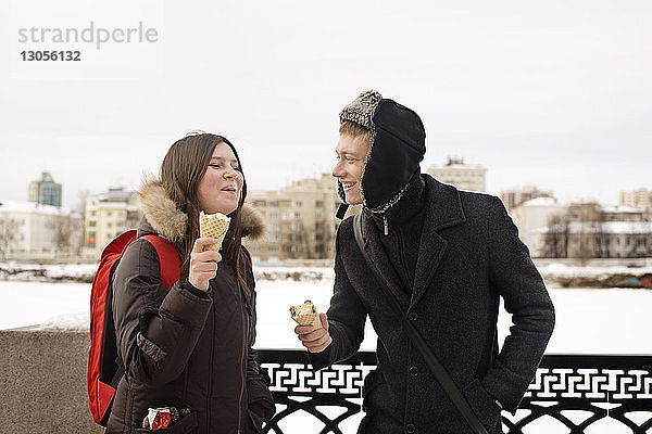 Glückliches Paar isst im Winter Eiscreme im Park