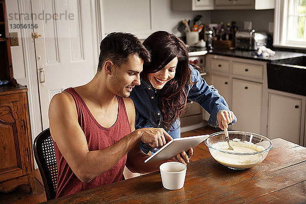 Mann zeigt seiner Freundin in der Küche einen Tablet-Computer