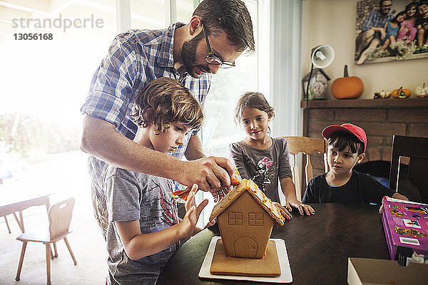 Familie schmückt Lebkuchenhaus zu Hause
