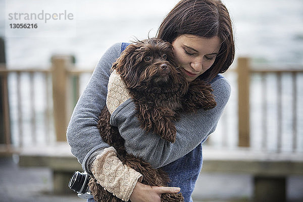 Frau umarmt Hund  während sie am Hudson River steht