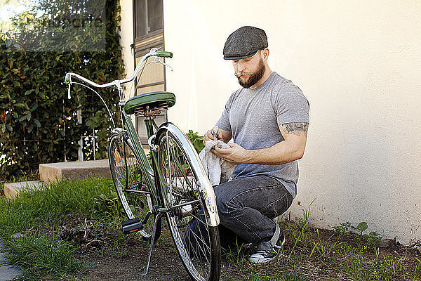 Mann reinigt Fahrrad auf Feld im Hinterhof
