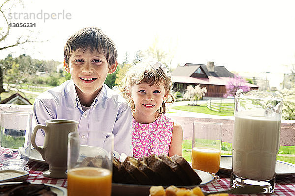 Porträt von Geschwistern  die beim Frühstück am Tisch sitzen