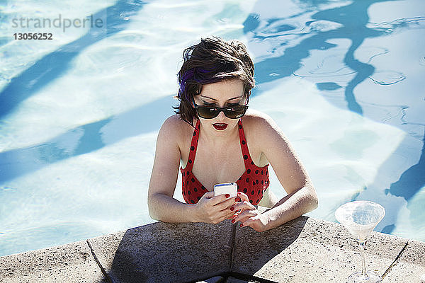 Junge Frau benutzt Smartphone im Schwimmbad