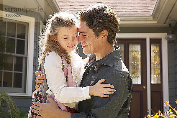 Glücklicher Vater mit Tochter vor dem Haus