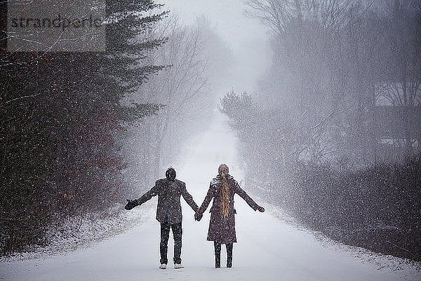 Paar  das im Winter auf verschneitem Feld stehend Händchen hält