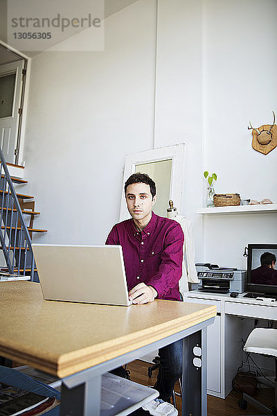 Portrait eines Geschäftsmannes mit Laptop am Tisch im Kreativbüro