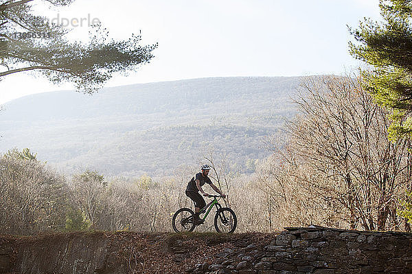 Mann fährt Mountainbike am Berg gegen klaren Himmel