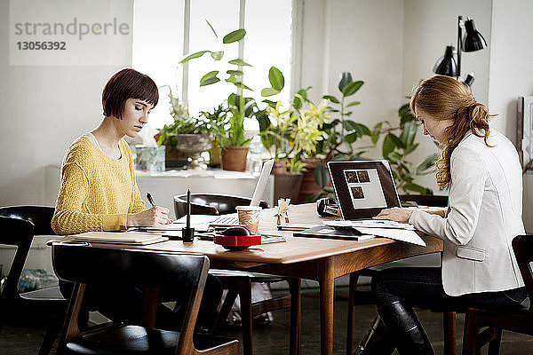 Weibliche Fotoredakteurinnen arbeiten am Tisch im Kreativbüro
