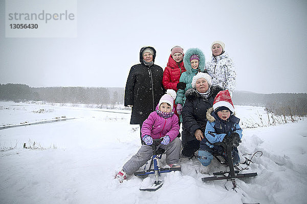 Glückliche Familie auf schneebedecktem Feld gegen den Himmel