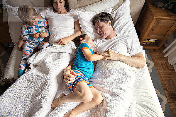 Draufsicht von Eltern  die mit Kindern zu Hause im Bett liegen