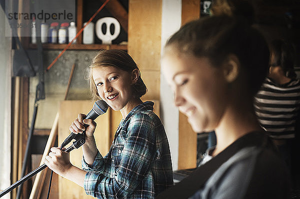 Mädchen sieht Freundin beim Singen im Aufnahmestudio an