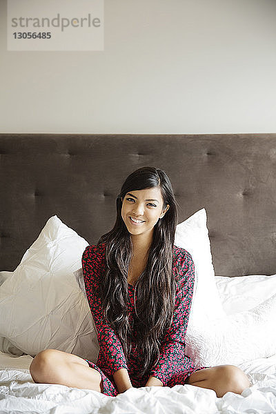 Porträt einer lächelnden Frau  die zu Hause auf dem Bett liegt