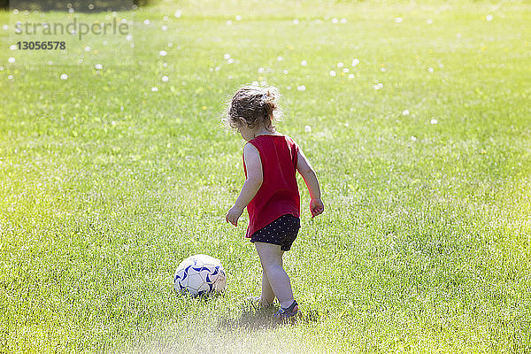 Rückansicht eines Mädchens beim Fussballspielen auf einem Rasenplatz