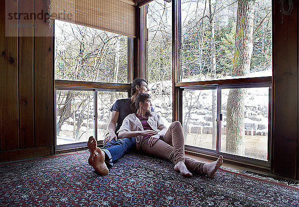 Paar  das zu Hause sitzend durchs Fenster schaut