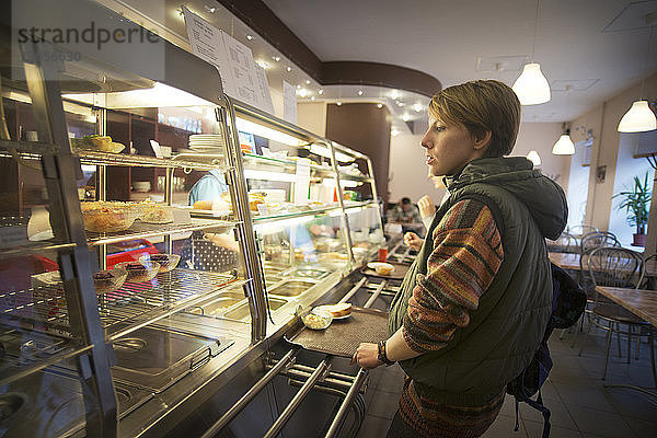 Frau betrachtet im Restaurant ausgestellte Speisen