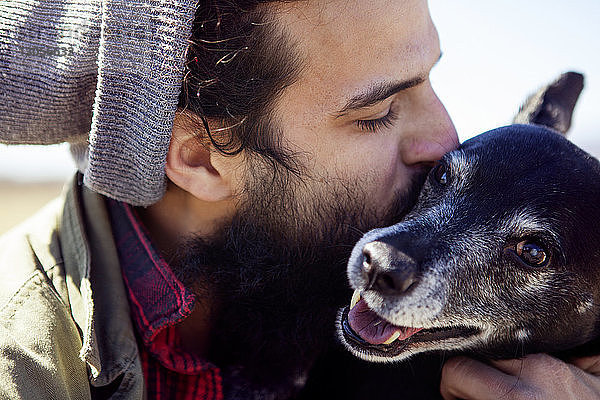 Nahaufnahme eines liebevollen Mannes  der einen Hund an einem sonnigen Tag küsst