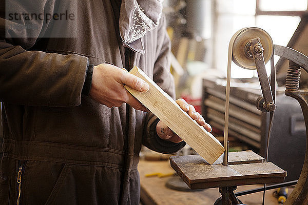 Beschnittenes Bild eines Mannes  der auf einer Maschine Holz formt