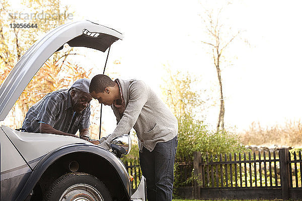 Vater und Sohn reparieren Auto gegen den Himmel