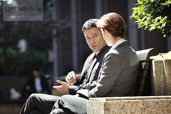 Geschäftsmann und Geschäftsfrau diskutieren auf der Bank sitzend
