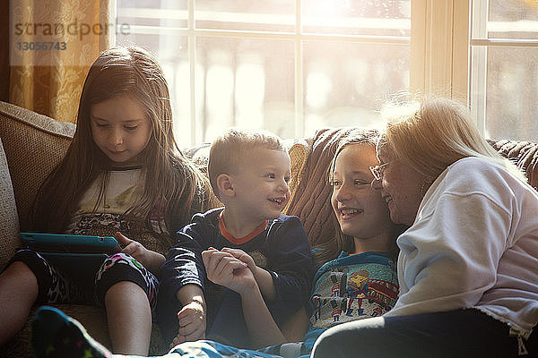 Glückliche Kinder sitzen zu Hause mit der Großmutter auf dem Sofa