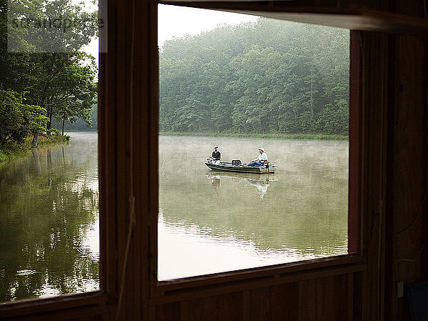Männer beim Angeln im Boot auf dem See sitzend durch Fenster gesehen