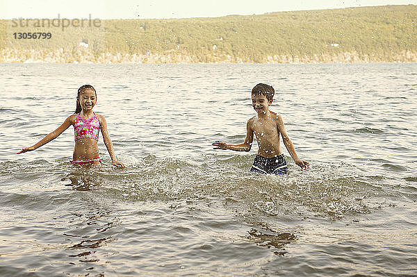Geschwister planschen Wasser im See