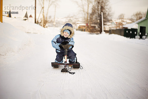 Porträt eines glücklichen Jungen  der im Winter auf einem Schlitten sitzt