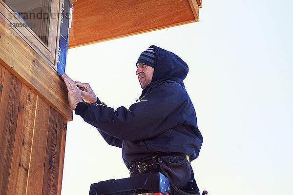 Niedrigwinkelansicht eines Arbeiters beim Hausbau vor klarem Himmel