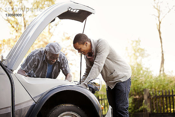 Glückliche Vater und Sohn reparieren Auto gegen den Himmel