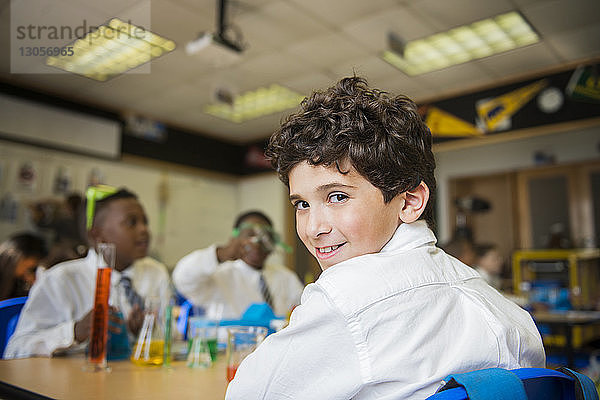 Porträt eines lächelnden Jungen  der im Labor am Tisch sitzt