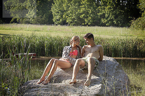 Junges Paar entspannt sich auf Felsen am Seeufer