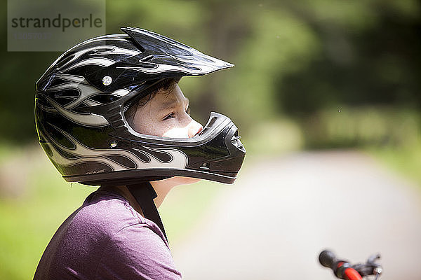 Nahaufnahme eines Jungen mit Sturzhelm beim Wegschauen