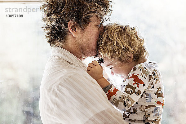 Seitenansicht eines Vaters  der die Stirn seines Sohnes küsst