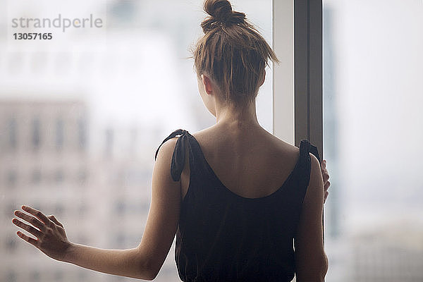 Rückansicht der am Fenster stehenden Frau