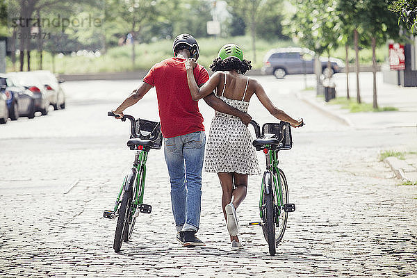 Rückansicht eines Paares mit dem Arm um den Arm auf einer Straße in der Stadt