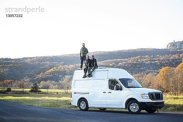 Freunde auf Wohnmobil gegen klaren Himmel