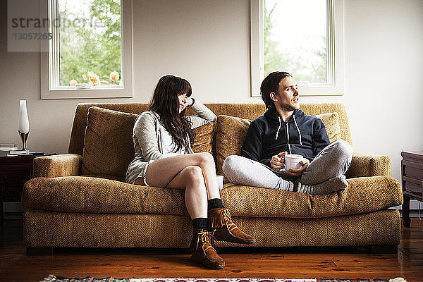 Ehepaar schaut weg  während es zu Hause auf dem Sofa sitzt