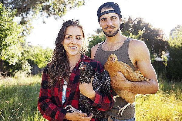 Porträt eines Ehepaares  das auf dem Feld stehende Hühner hält