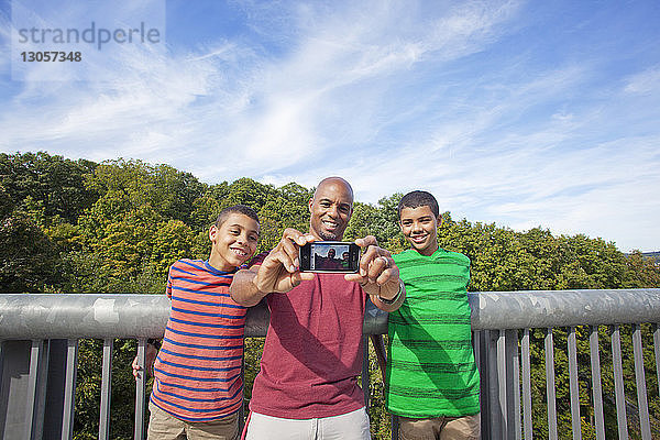 Mann fotografiert  während er mit seinem Sohn am Himmel steht