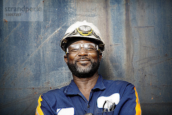 Nahaufnahme eines lächelnden männlichen Arbeiters  der an einer Metallwand steht