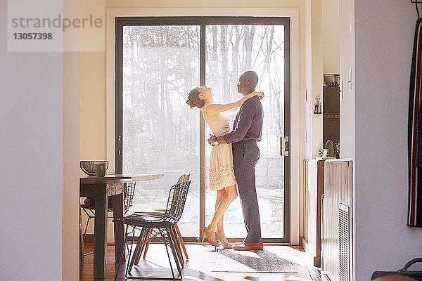 Seitenansicht eines zu Hause am Fenster stehenden Paares