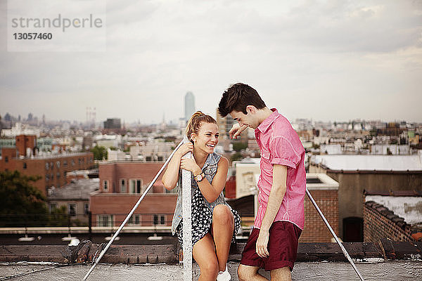 Glückliches junges Paar auf Gebäudeterrasse gegen die Stadt