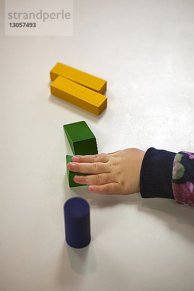 Hochwinkelansicht eines Mädchens  das Spielzeugblöcke auf einem Tisch in der Vorschule berührt