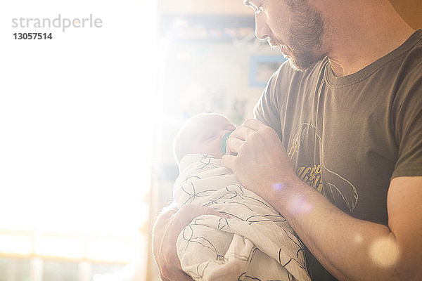 Vater legt Schnuller an sonnigen Tagen zu Hause auf die kleine Tochter