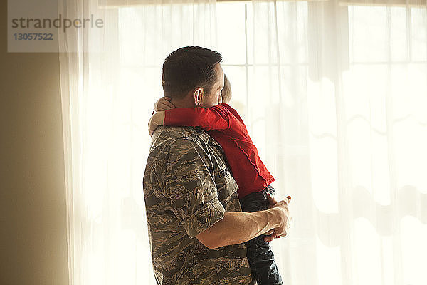 Seitenansicht eines Vaters  der seinen Sohn zu Hause umarmt