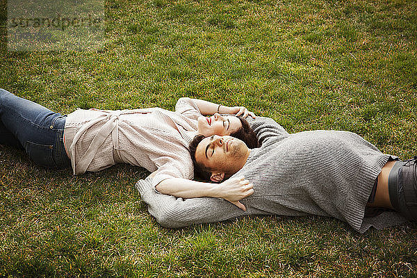 Hochwinkelaufnahme eines Mannes und einer Frau  die auf einem Grasfeld im Park liegen