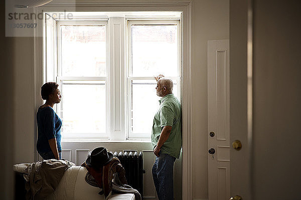 Vater und Tochter stehen zu Hause am Fenster