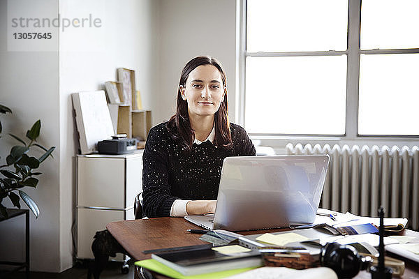Porträt einer jungen Geschäftsfrau  die im Kreativbüro am Laptop arbeitet